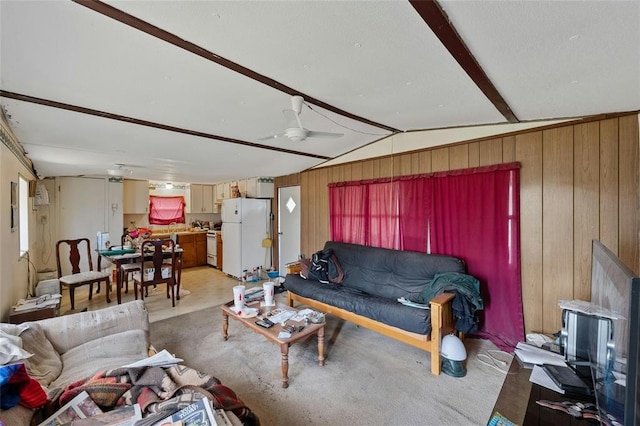 carpeted living room with vaulted ceiling, ceiling fan, and wood walls