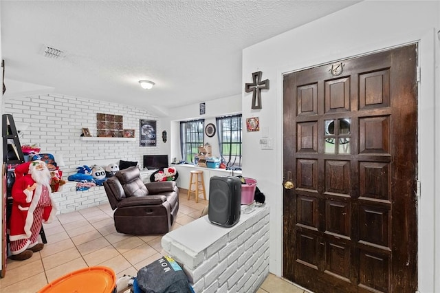 living room with light tile patterned flooring, brick wall, and a textured ceiling