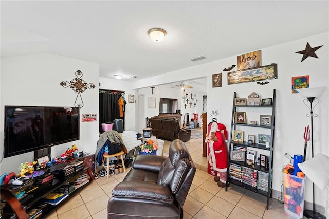 living room featuring ceiling fan, light tile patterned floors, a textured ceiling, and vaulted ceiling