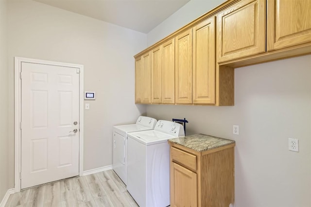 laundry area featuring cabinets, light wood-type flooring, and separate washer and dryer