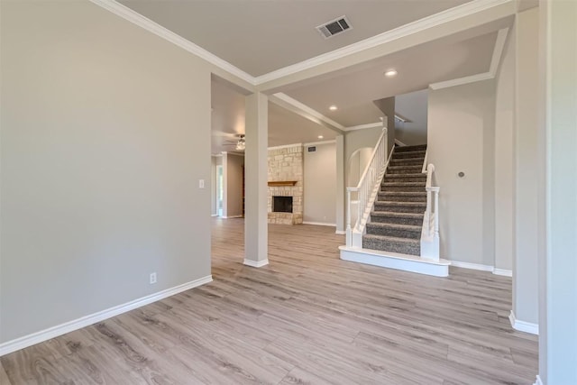 unfurnished living room featuring ceiling fan, light hardwood / wood-style floors, a stone fireplace, and crown molding