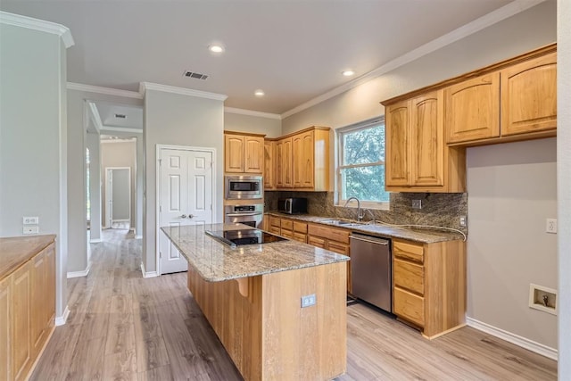 kitchen with light stone countertops, sink, stainless steel appliances, crown molding, and a kitchen island