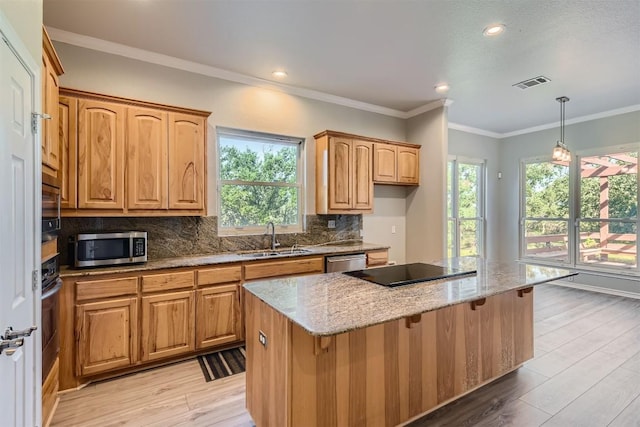 kitchen featuring light stone counters, stainless steel appliances, a kitchen island, and sink