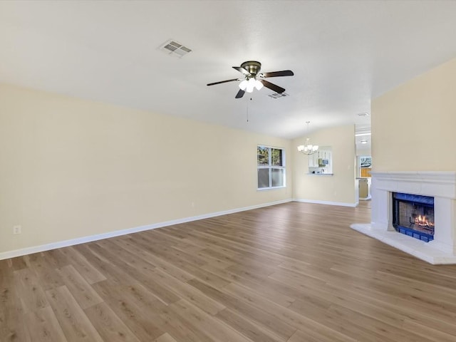 unfurnished living room featuring light hardwood / wood-style flooring, ceiling fan with notable chandelier, and vaulted ceiling