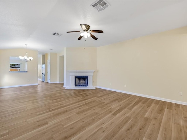 unfurnished living room with lofted ceiling, ceiling fan with notable chandelier, and light wood-type flooring