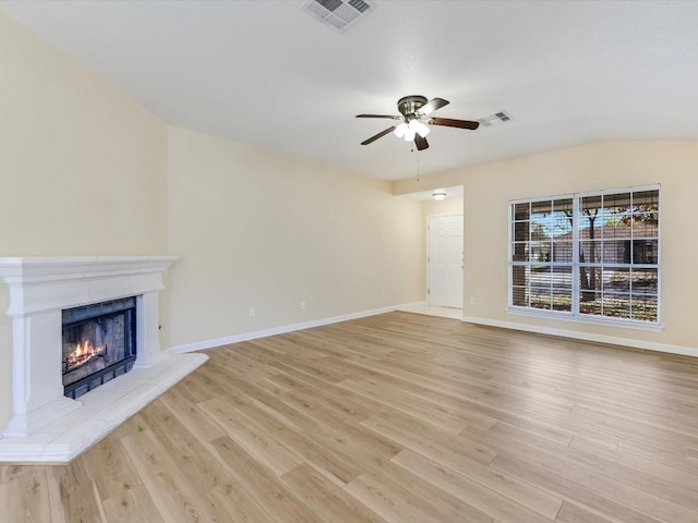 unfurnished living room with ceiling fan, light hardwood / wood-style floors, lofted ceiling, and a tile fireplace