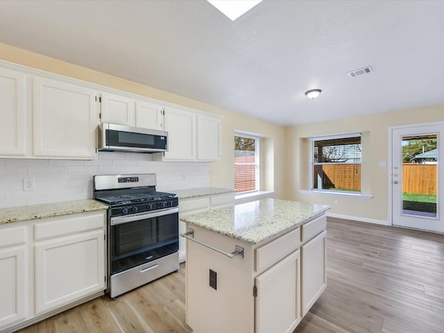 kitchen with a center island, stainless steel appliances, white cabinetry, and plenty of natural light