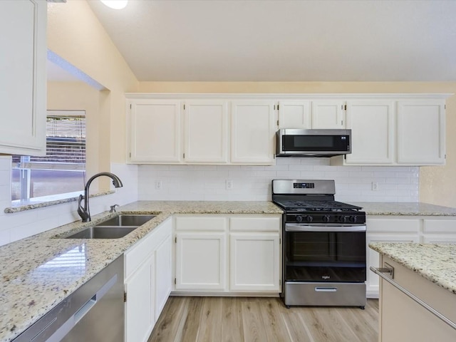 kitchen with appliances with stainless steel finishes, light wood-type flooring, white cabinetry, and sink