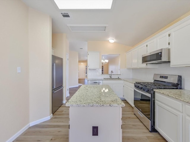 kitchen with light stone countertops, stainless steel appliances, a kitchen island, and sink