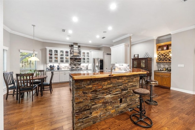 kitchen with white cabinets, backsplash, hanging light fixtures, and wall chimney exhaust hood