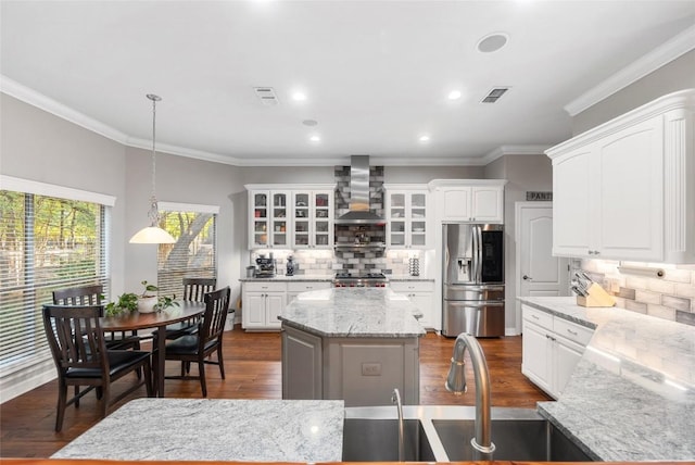 204 Woodland Park, Georgetown, TX 78633 - kitchen featuring stainless steel fridge, wall chimney exhaust hood, glass insert cabinets, tasteful backsplash, and white cabinetry