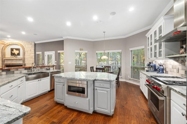 204 Woodland Park, Georgetown, TX 78633 - kitchen featuring stainless steel appliances, wall chimney range hood, a sink, backsplash, and white cabinetry