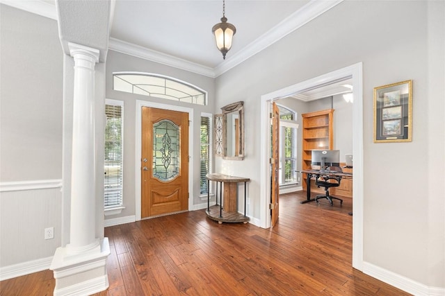 foyer entrance with decorative columns, a wealth of natural light, crown molding, and hardwood / wood-style flooring