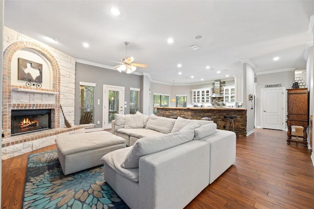 living room with ceiling fan, crown molding, dark hardwood / wood-style floors, and a brick fireplace