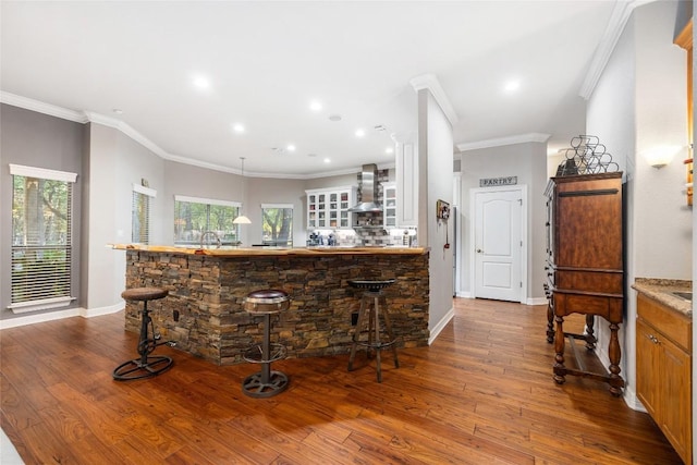 bar featuring hardwood / wood-style flooring, wall chimney range hood, and ornamental molding