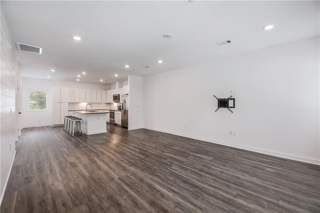 unfurnished living room with dark wood-type flooring, a sink, visible vents, and recessed lighting