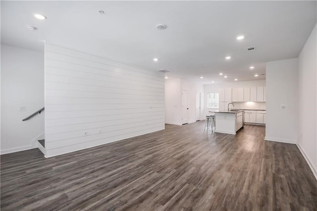 unfurnished living room featuring dark wood-style floors, recessed lighting, visible vents, and a sink