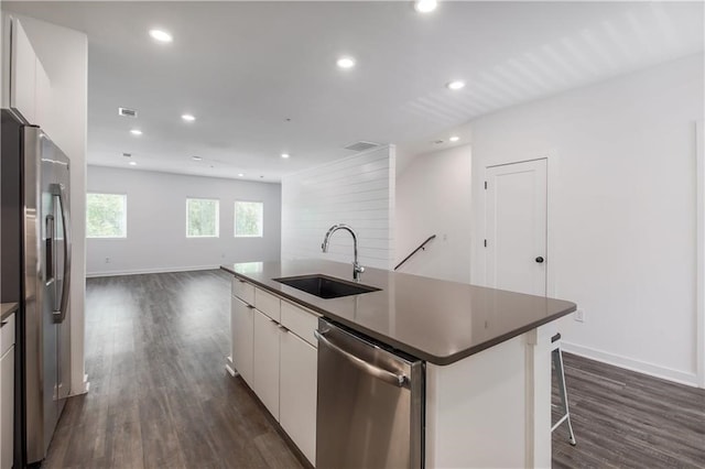 kitchen with sink, dark hardwood / wood-style floors, an island with sink, stainless steel appliances, and white cabinets