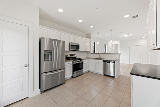 kitchen with stainless steel appliances, sink, light tile patterned floors, white cabinetry, and hanging light fixtures