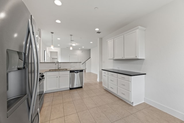 kitchen with kitchen peninsula, appliances with stainless steel finishes, decorative light fixtures, white cabinets, and light tile patterned flooring