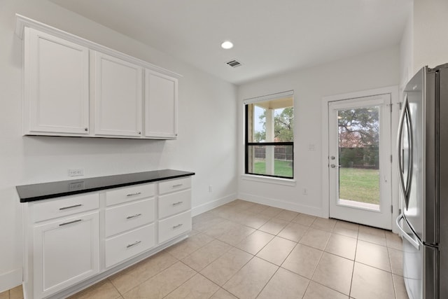 kitchen featuring white cabinets, stainless steel fridge, and light tile patterned floors