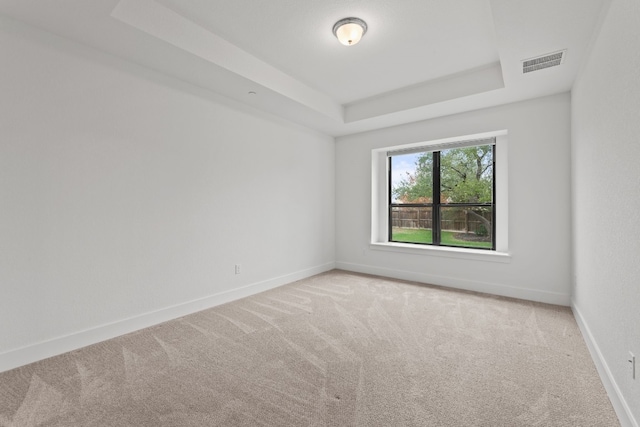 carpeted empty room with a tray ceiling