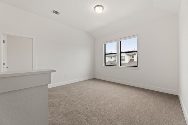 carpeted empty room with lofted ceiling