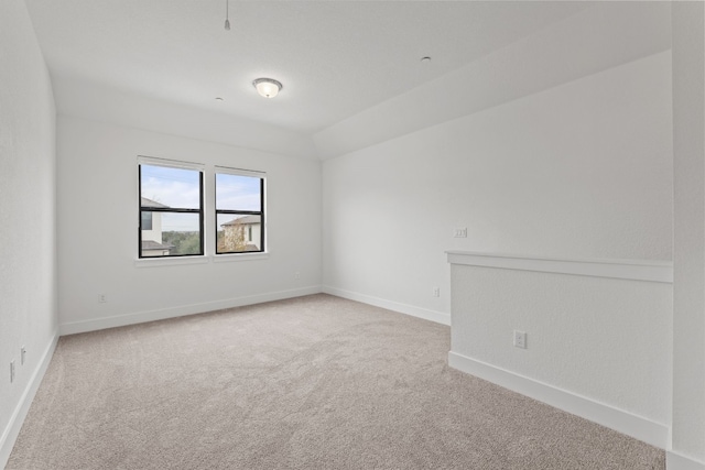 carpeted empty room with lofted ceiling