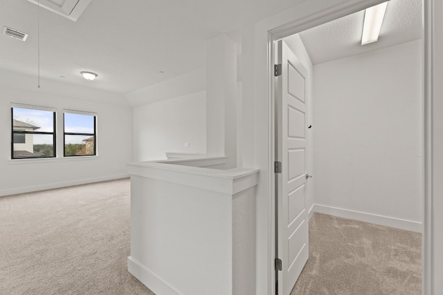 corridor with light colored carpet and vaulted ceiling