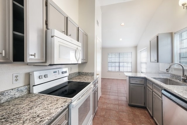 kitchen featuring sink, light stone counters, tile patterned floors, vaulted ceiling, and white appliances