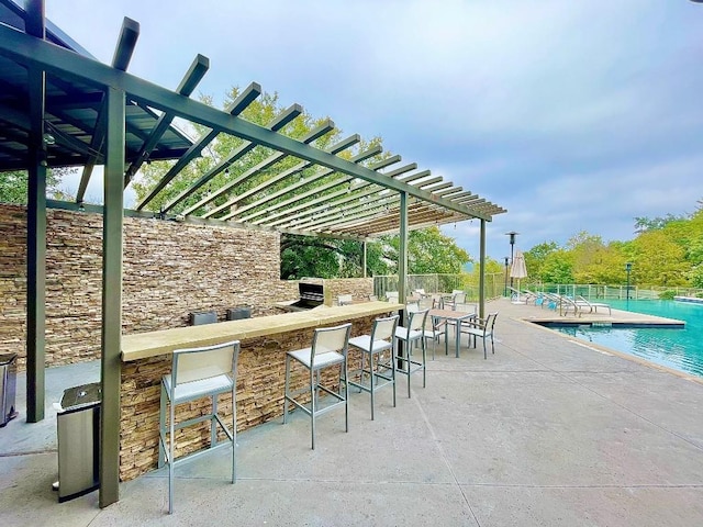 view of patio / terrace with exterior bar and a community pool