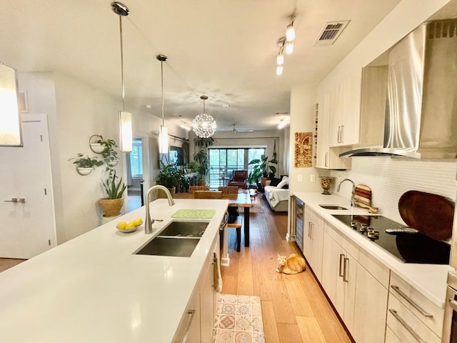 kitchen featuring decorative light fixtures, light hardwood / wood-style floors, sink, and range hood