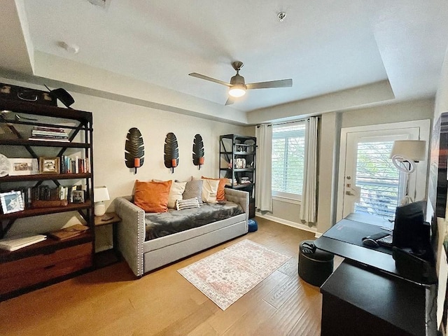 sitting room featuring hardwood / wood-style flooring, ceiling fan, and a tray ceiling