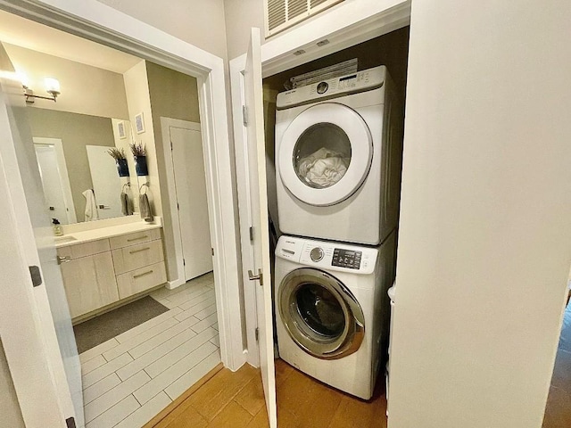 laundry area featuring light hardwood / wood-style flooring and stacked washer and clothes dryer