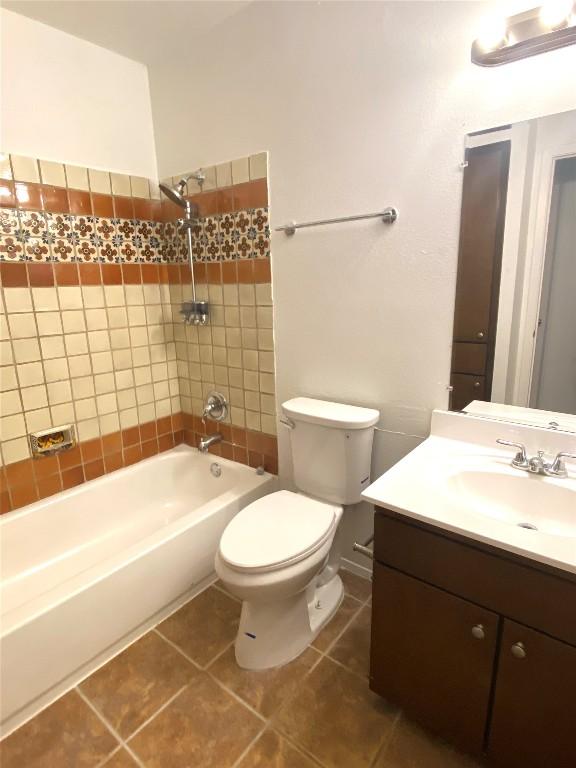 full bathroom featuring tile patterned flooring, tiled shower / bath combo, toilet, and vanity