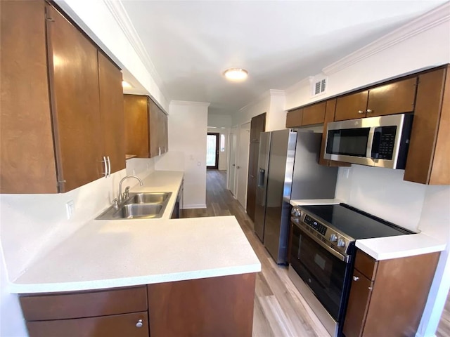 kitchen featuring light wood-type flooring, sink, appliances with stainless steel finishes, and ornamental molding