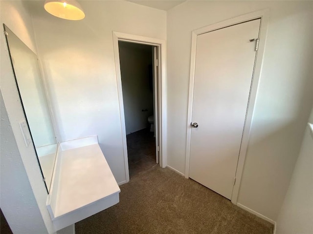 hallway with dark colored carpet