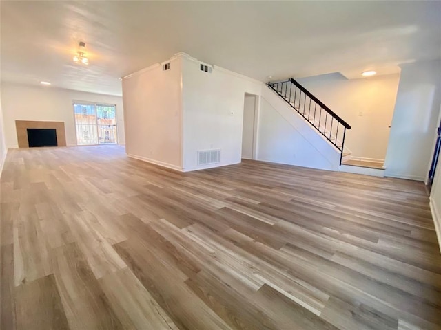 unfurnished living room with light hardwood / wood-style floors and ornamental molding