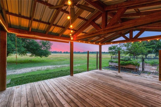 deck at dusk featuring a yard, a rural view, and ceiling fan