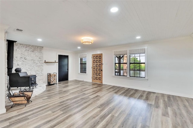 living room with a wood stove, crown molding, and light hardwood / wood-style floors