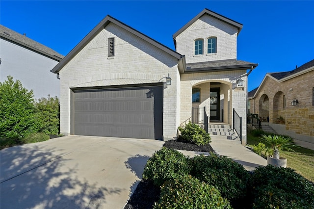 french provincial home featuring driveway, a garage, and brick siding