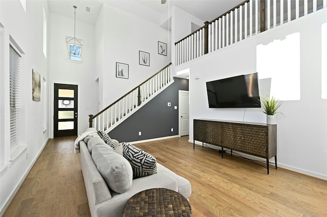 living area with baseboards, stairway, and wood finished floors