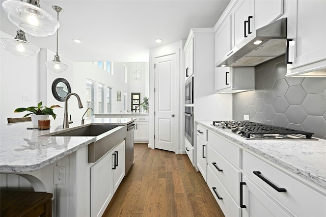 kitchen featuring stainless steel appliances, white cabinets, ventilation hood, and light stone countertops