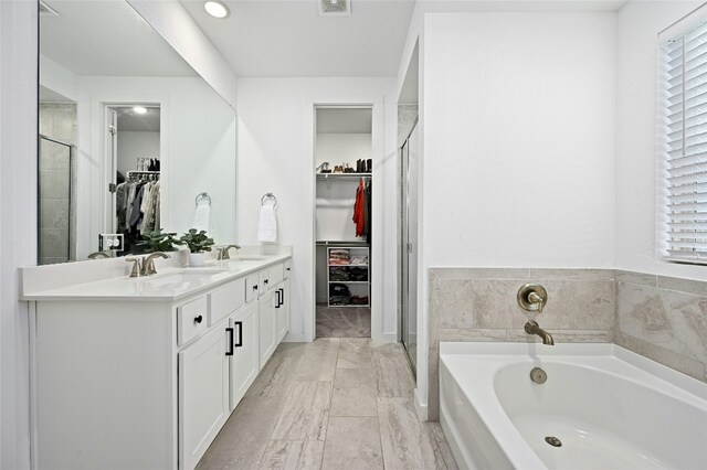 bathroom with a garden tub, a spacious closet, a sink, and a shower stall