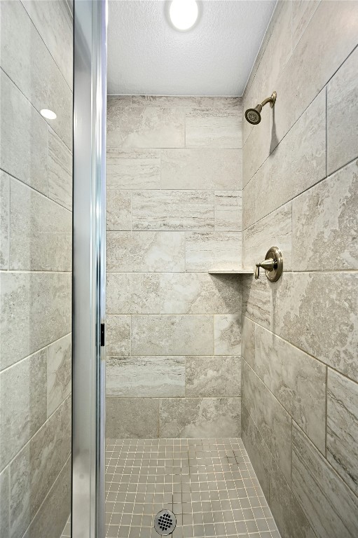 bathroom with a shower stall and a textured ceiling