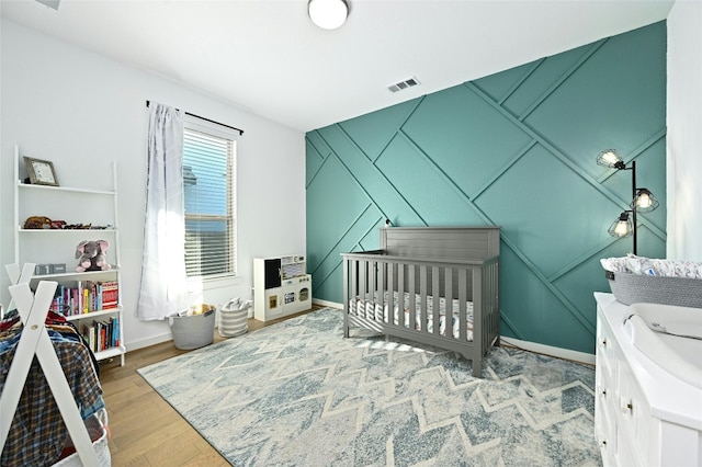 bedroom featuring baseboards, visible vents, and wood finished floors