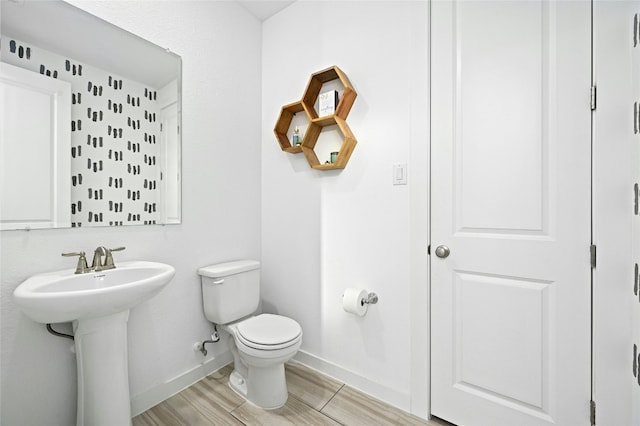 bathroom with wood finished floors, a sink, toilet, and baseboards