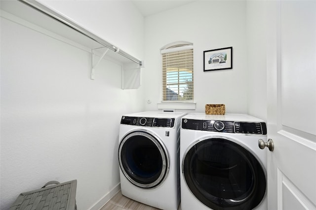 clothes washing area with laundry area, light wood-style floors, washer and clothes dryer, and baseboards