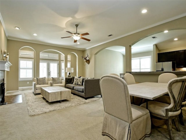 dining space featuring ceiling fan, light colored carpet, and ornamental molding