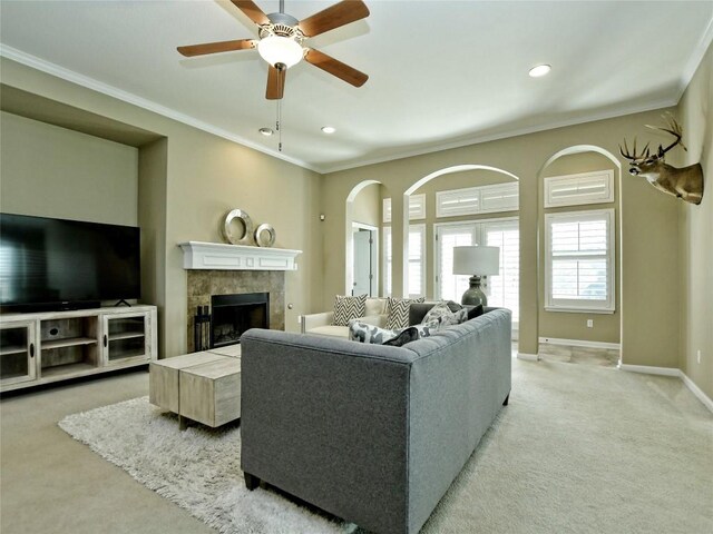 carpeted living room featuring a tile fireplace, ceiling fan, and crown molding